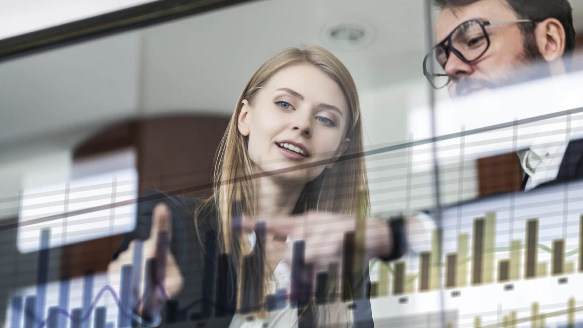 Two business persons in front of futuristic display discussing financial graph