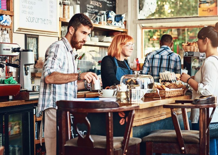 Barista, woman and cafe as waitress in small business with customer in restaurant or coffee shop. Working people, cafeteria and client for food service with entrepreneur in startup