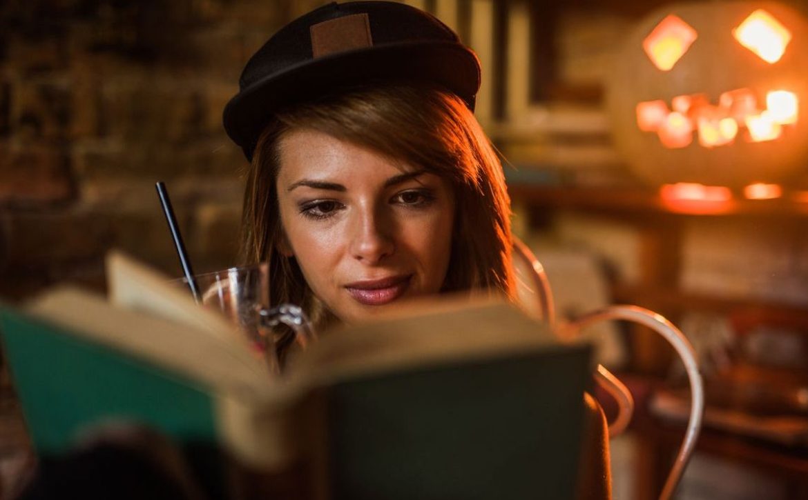 Beautiful woman with cap reading a novel.