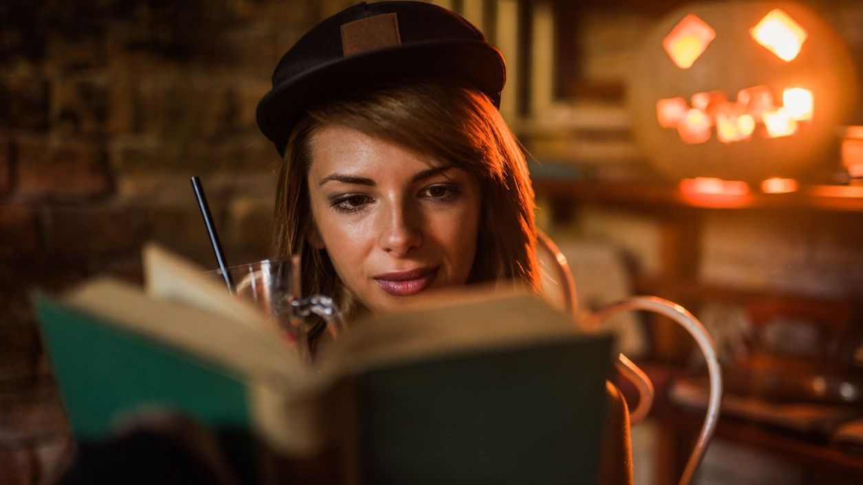 Beautiful woman with cap reading a novel.