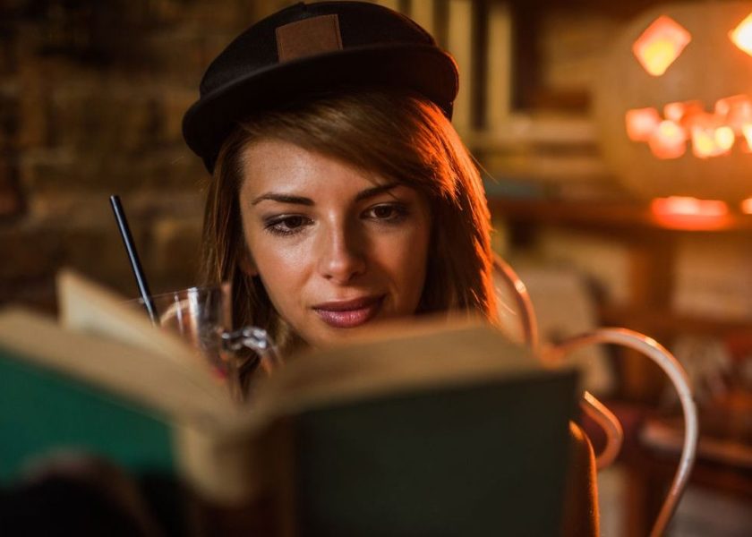 Beautiful woman with cap reading a novel.