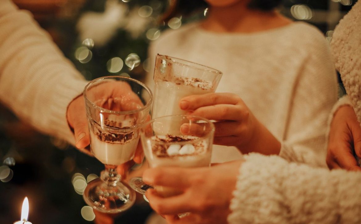 Family drinking homemade eggnog by the Christmas tree having fun