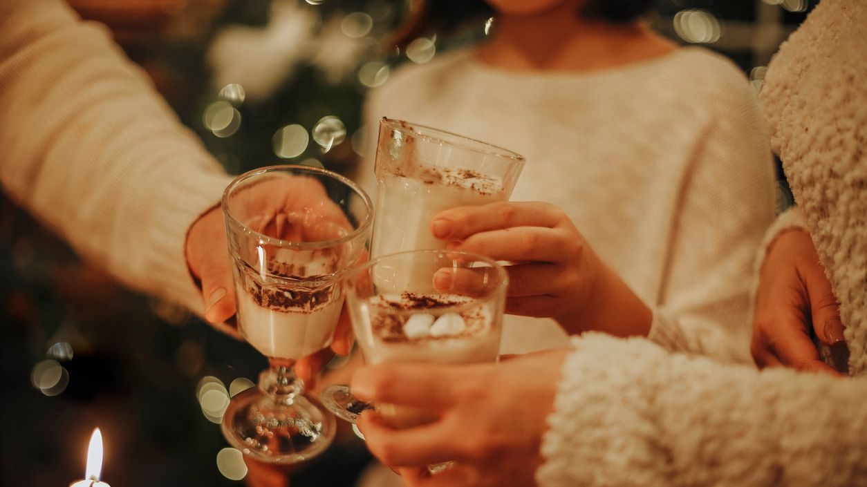 Family drinking homemade eggnog by the Christmas tree having fun