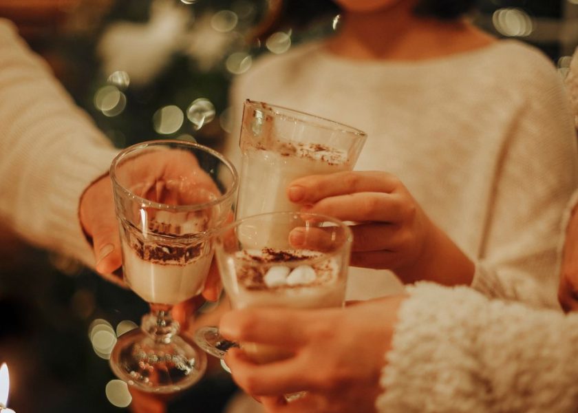 Family drinking homemade eggnog by the Christmas tree having fun