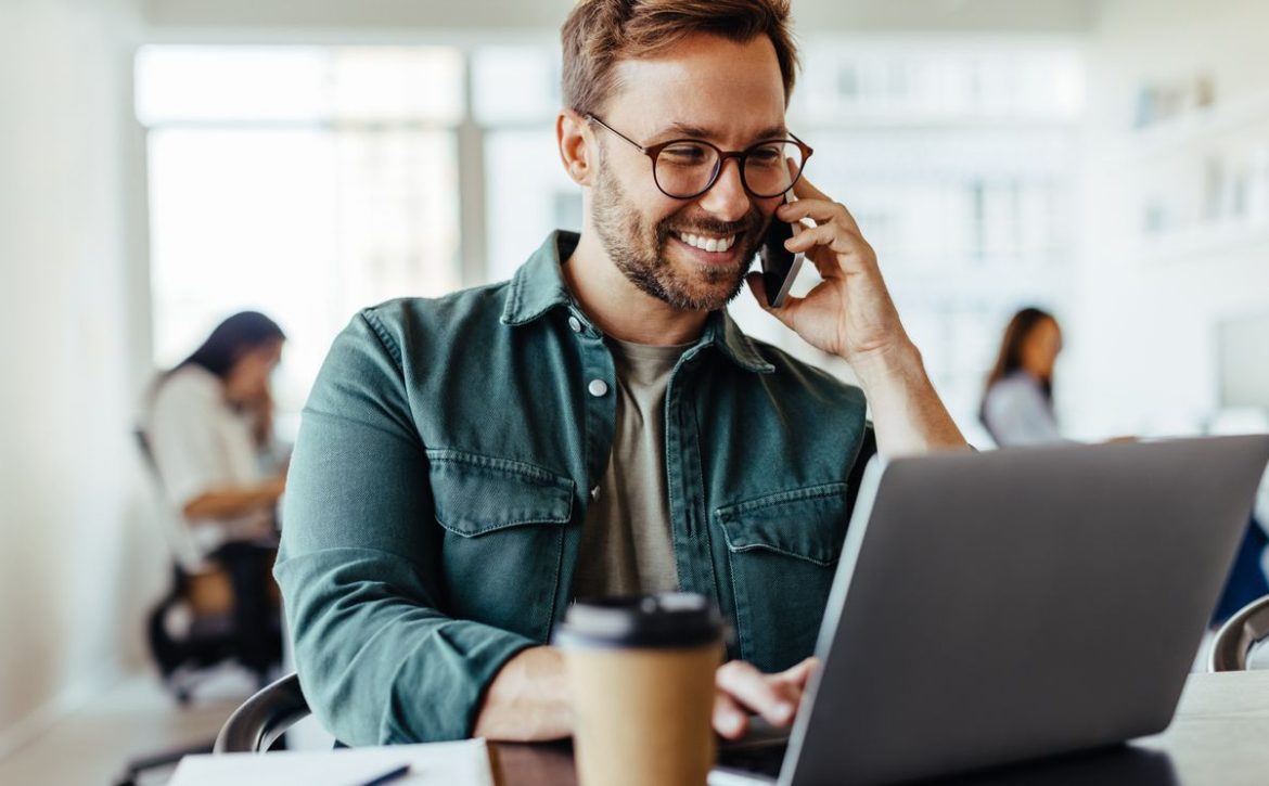 Male software designer speaking to a client on the phone in an office