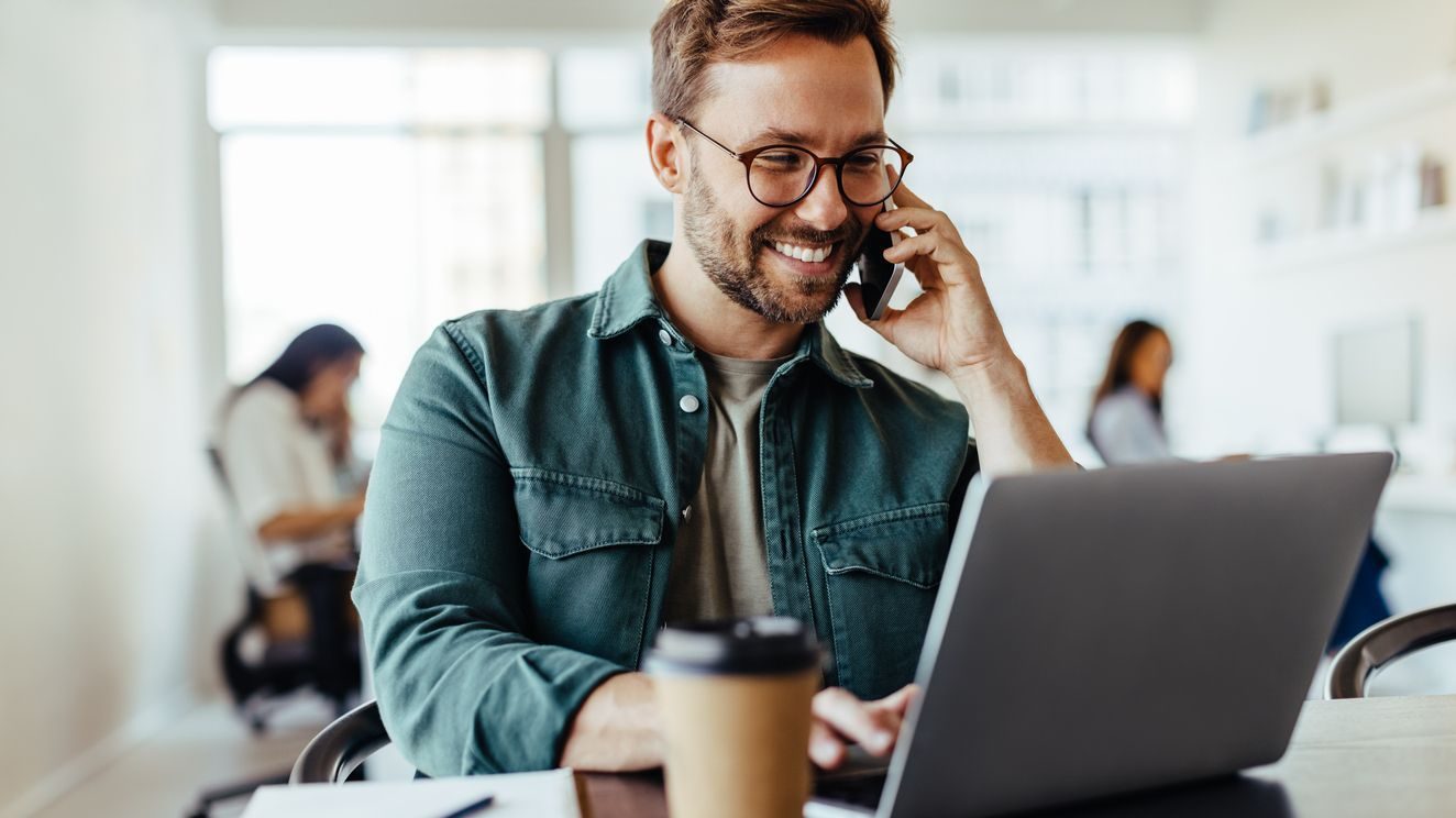 Male software designer speaking to a client on the phone in an office