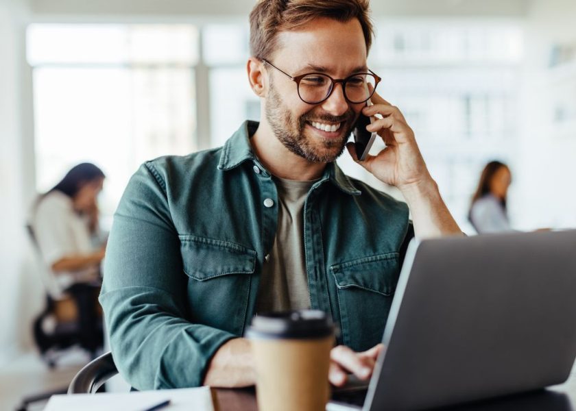 Male software designer speaking to a client on the phone in an office